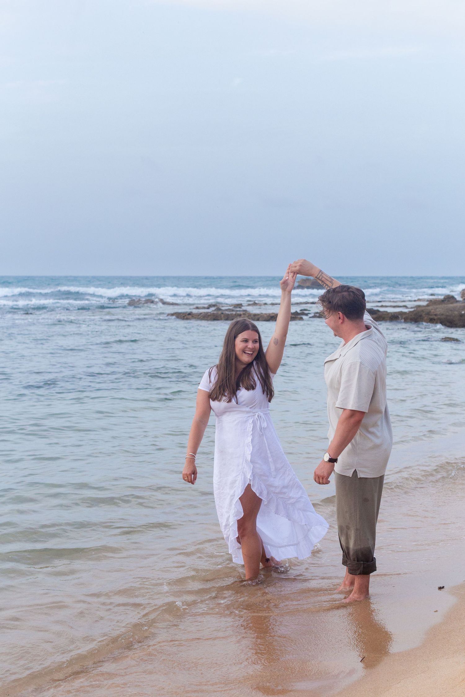 Couples portrait at water's edge on the beach at Balneario del Escambrón in Old San Juan, Puerto Rico.