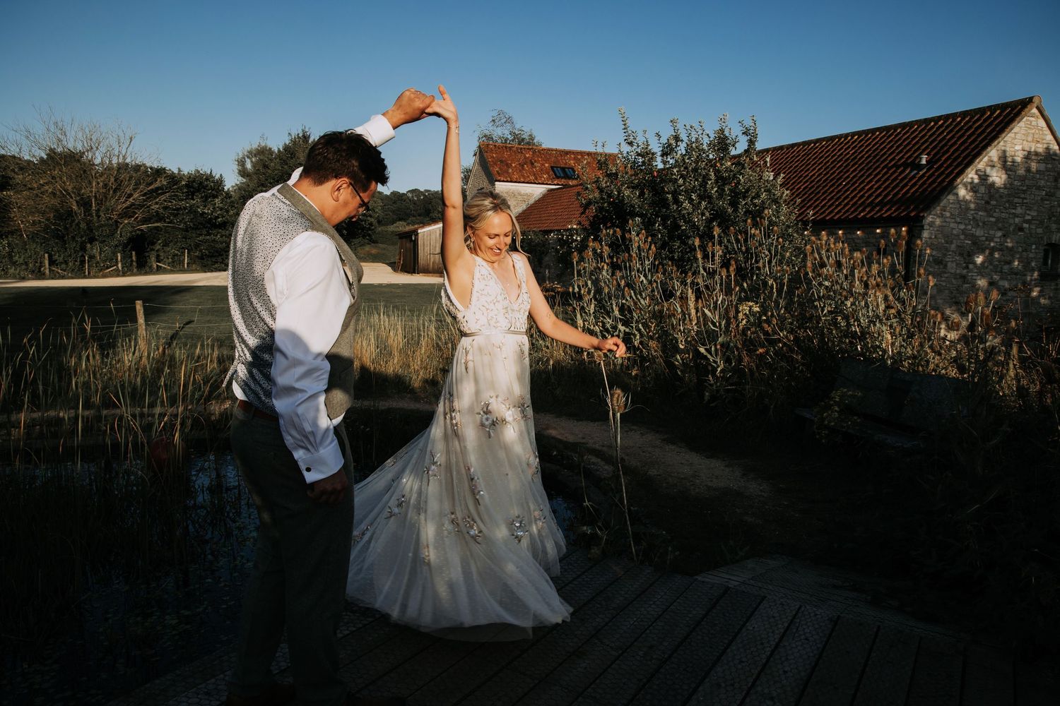 Bride and groom dancing together outdoors in warm evening light during their wedding celebration.