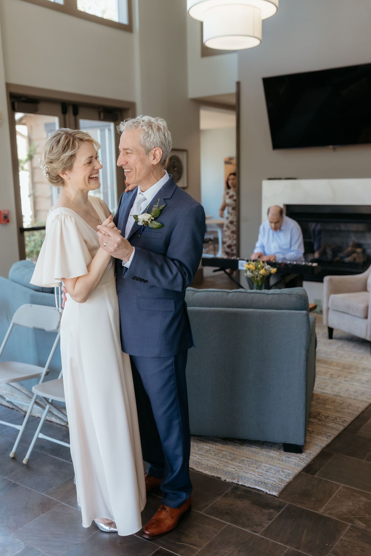 Elegant middle-aged couple sharing a first dance in wedding attire, bride in white gown and groom in navy suit.