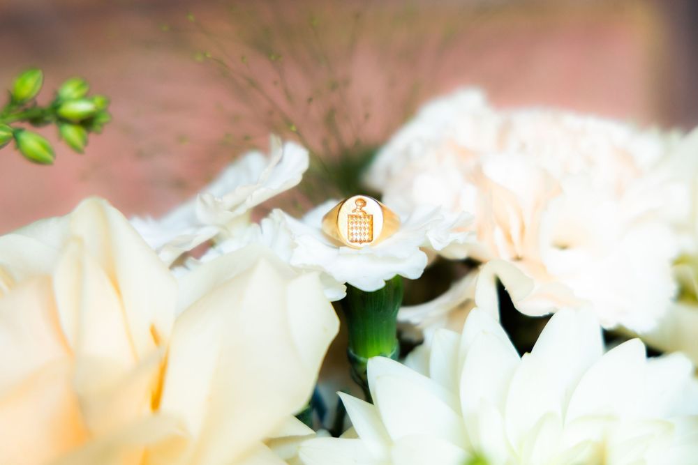 Gold wedding ring resting on white dahlia and cream roses in an elegant bridal bouquet.