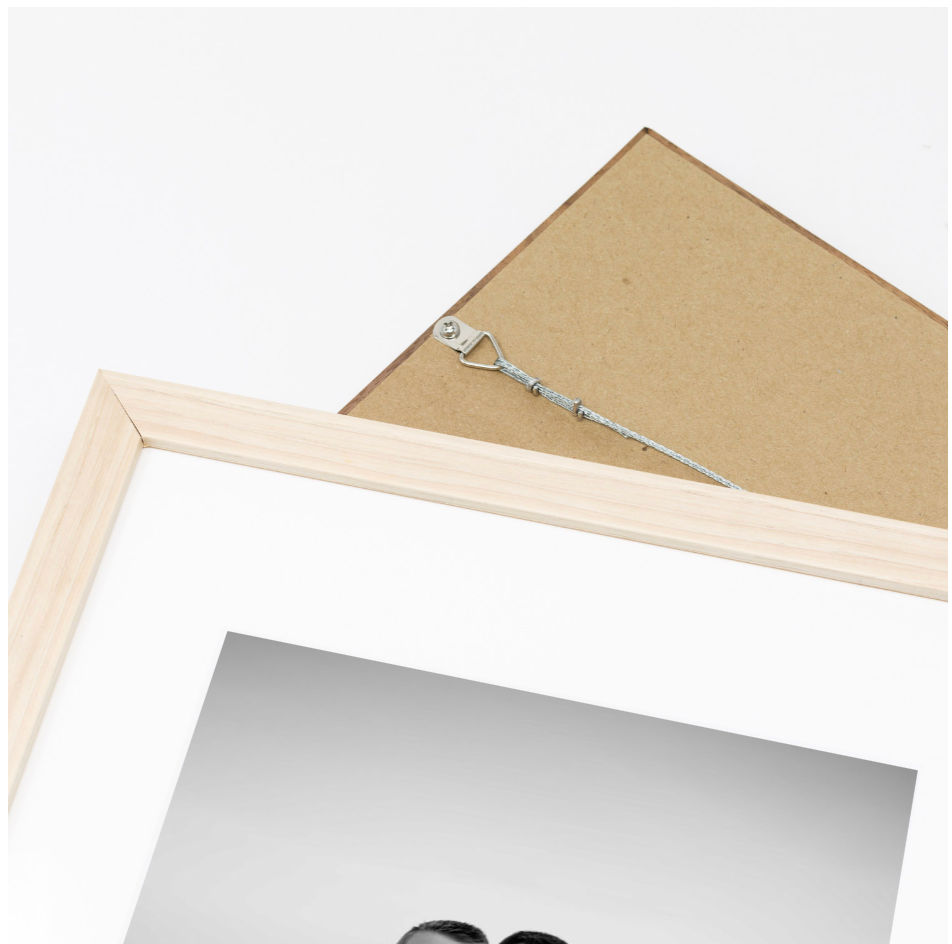 Light wood and white picture frame showing back mounting hardware and partial front view with photo mat.