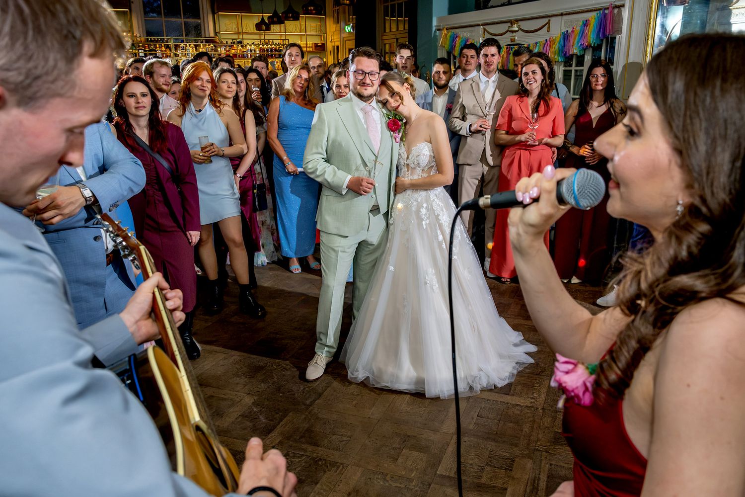 Zus van de bruid zingt samen met een begeleider op gitaar voor het bruidspaar tijdens het feest bij De Smaeckkamer in Beverwijk