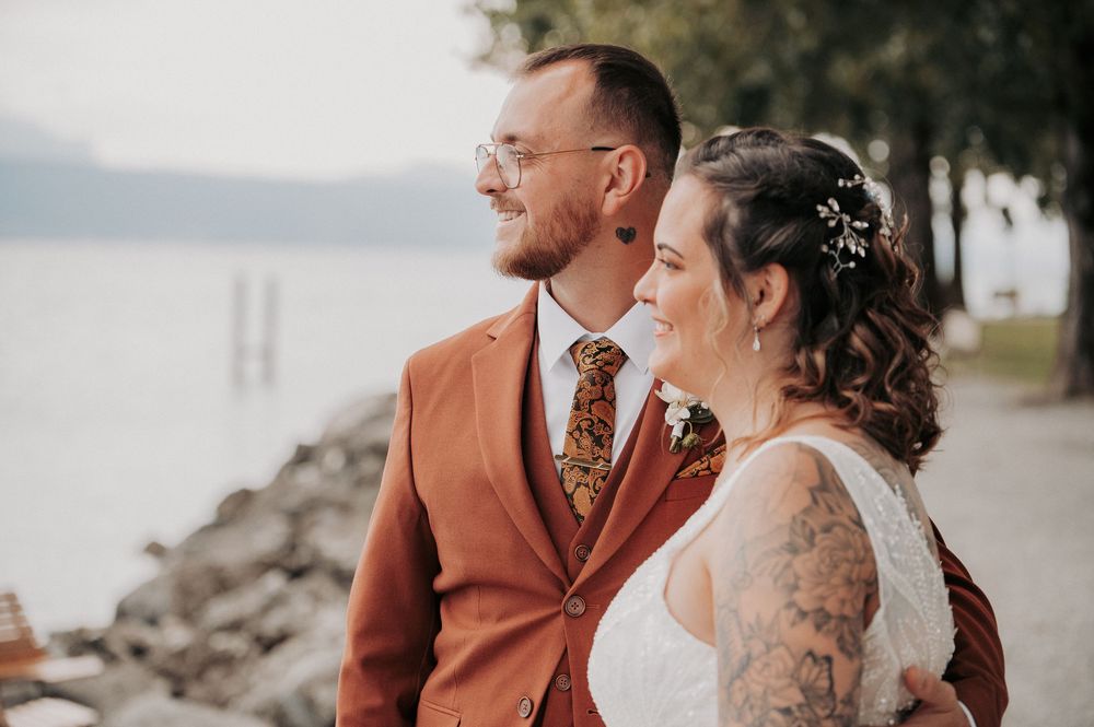 A couple in wedding attire shares an intimate moment by the water's edge.