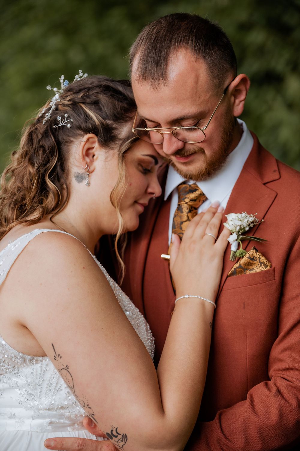 A couple in rustic wedding attire shares an emotional moment during their outdoor photo session.
