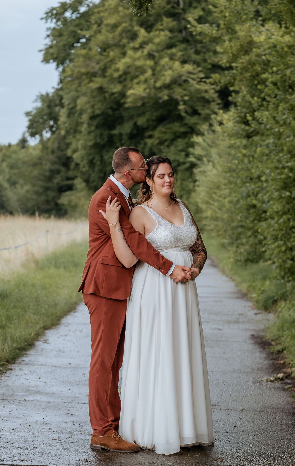 Wedding couple shares intimate poses on a gravel path surrounded by greenery.