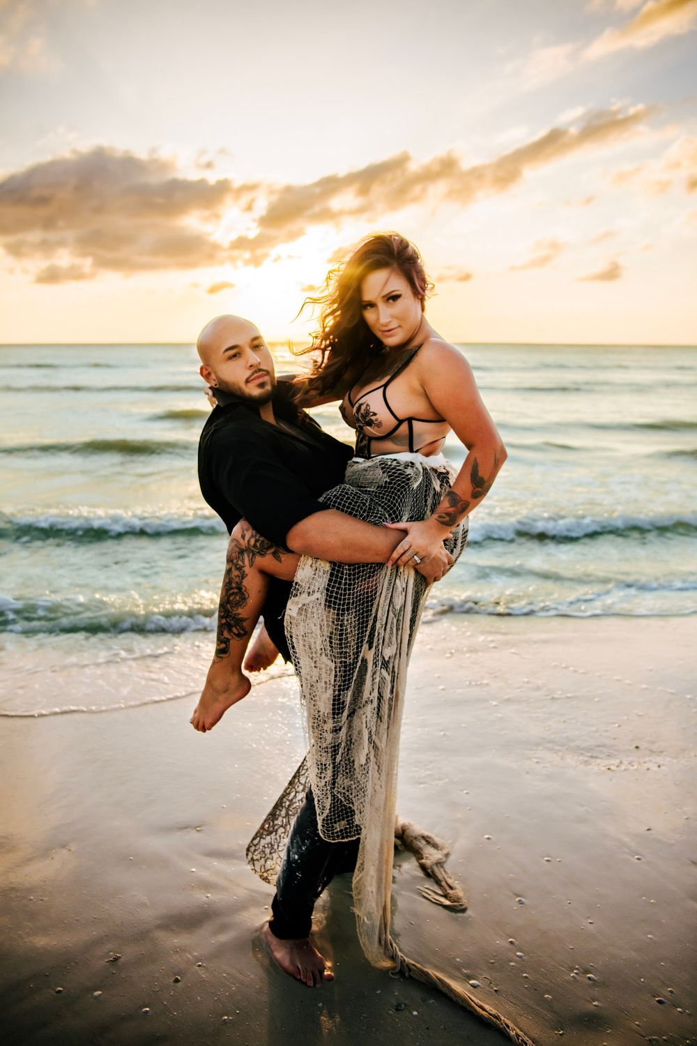 Intimate beach couples portrait in Dunedin, Florida with ocean waves, golden light, and dramatic sunset skies.