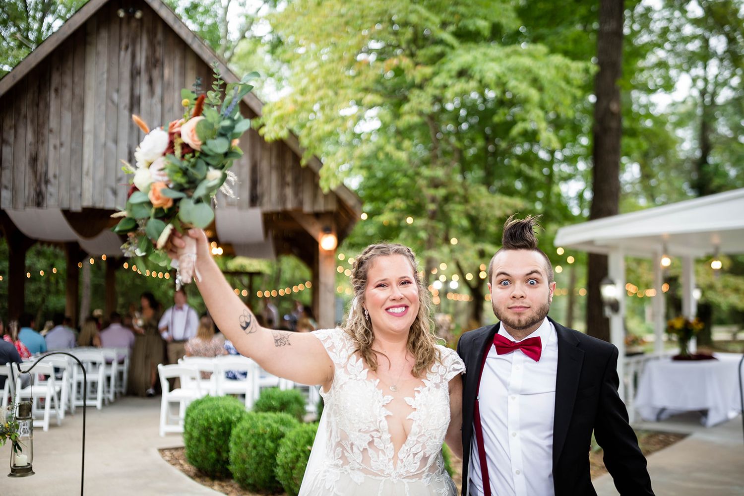 Bride raising her bouquet with her groom at an outdoor barn wedding northeast of Fayetteville, Arkansas