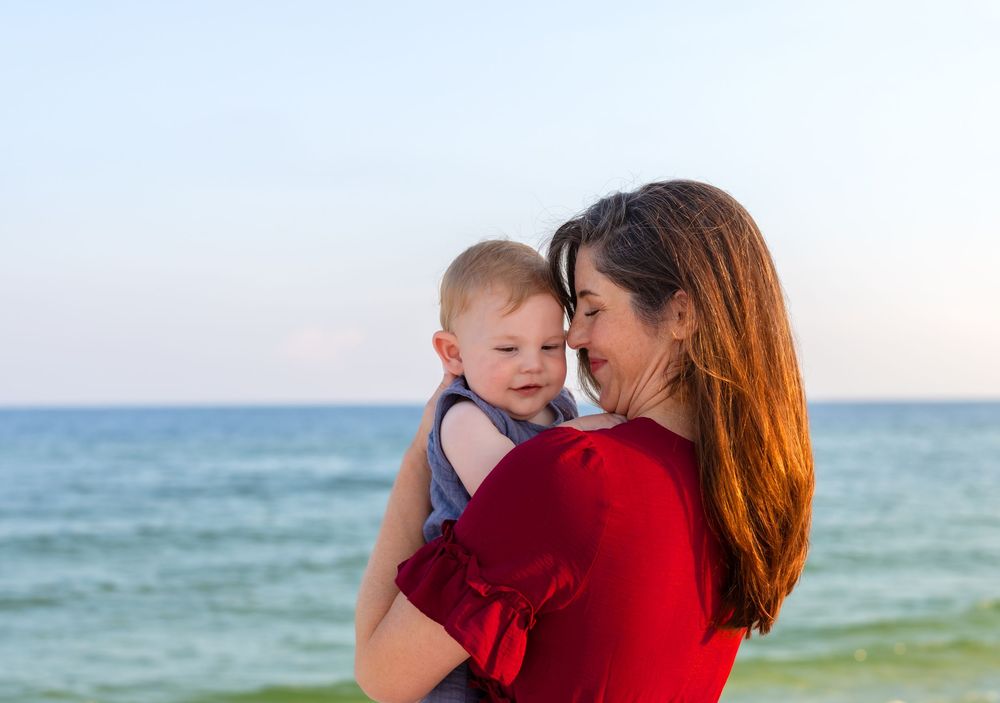 Golden hour family portrait of parents and children waling along the shoreline in Navarre Beach, Florida.