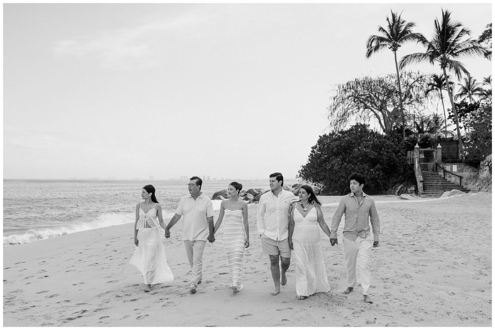 Puerto Vallarta Family Photographer captures Beach Family Photos of a group walking hand in hand along a tropical beach shoreline.