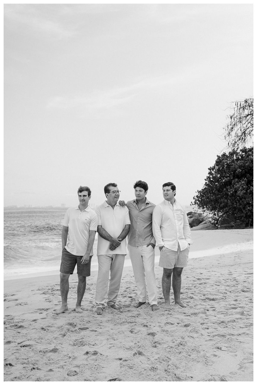 Puerto Vallarta Family Photographer captures Family Portraits of a father and sons posing together on a sandy beach.