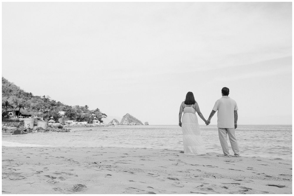 Puerto Vallarta Family Photographer captures Family Photo Session moments of a couple holding hands along a sandy beach with ocean views.