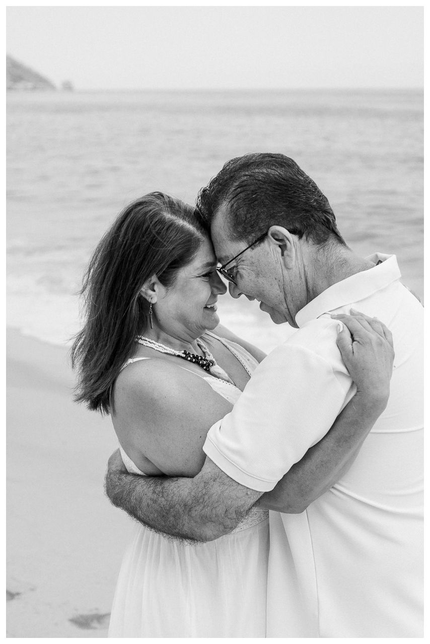 Puerto Vallarta Family Photographer captures Candid Family Photos of a couple embracing and smiling together on a quiet sandy beach.