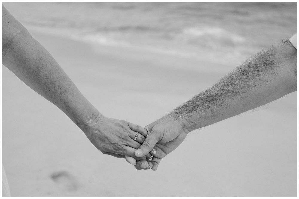 Puerto Vallarta Family Photographer captures Candid Family Photos featuring a couple holding hands together on a sandy beach.