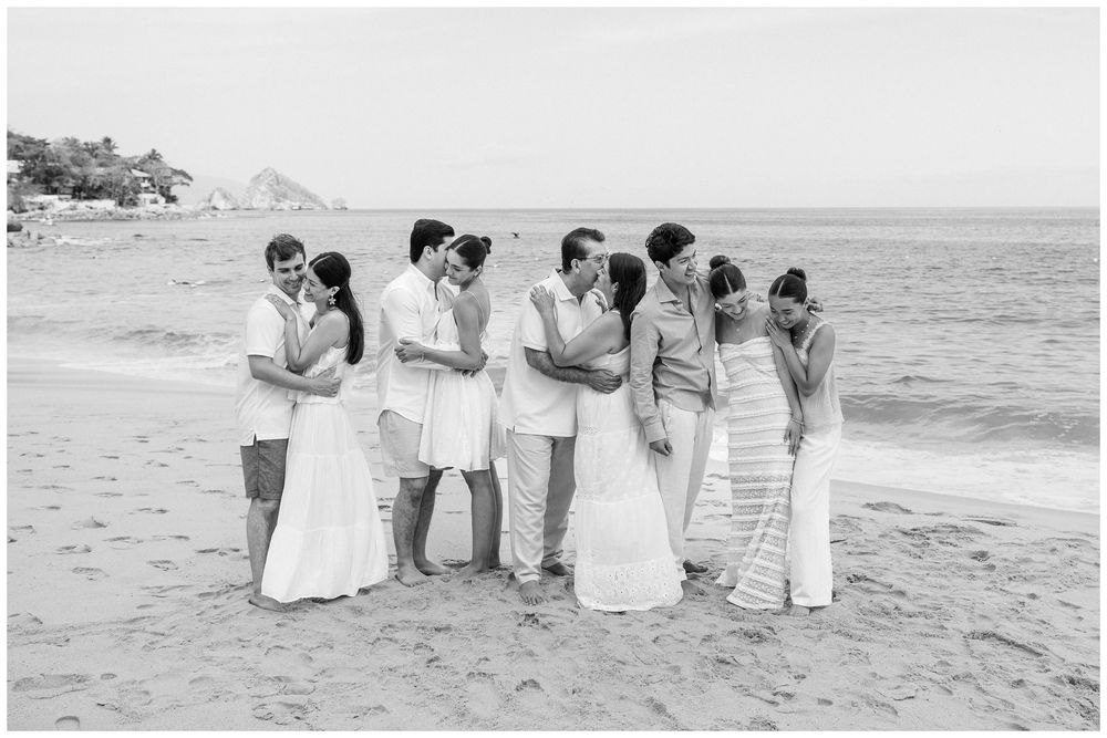 Puerto Vallarta Family Photographer captures Family Portraits of parents and children embracing together on a sandy beach by the ocean.