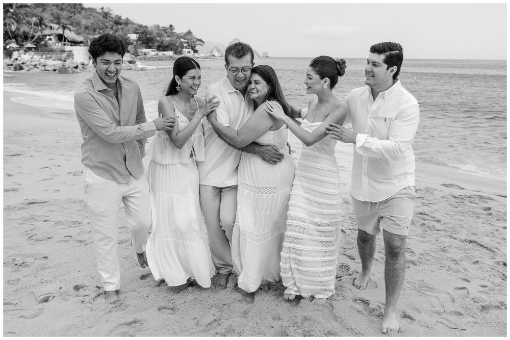 Puerto Vallarta Family Photographer captures Beach Photoshoot moments of six family members laughing together on a sandy beach by the ocean.