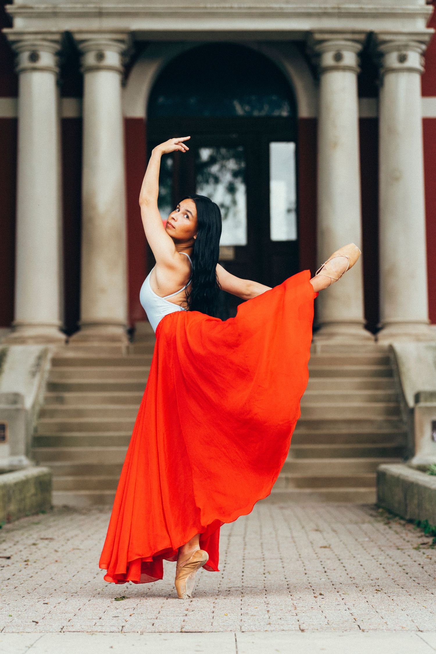 professional Senior portrait photographer captures dancer's attitude derriere before the crown point, IN Old Lake County Courthouse columns.