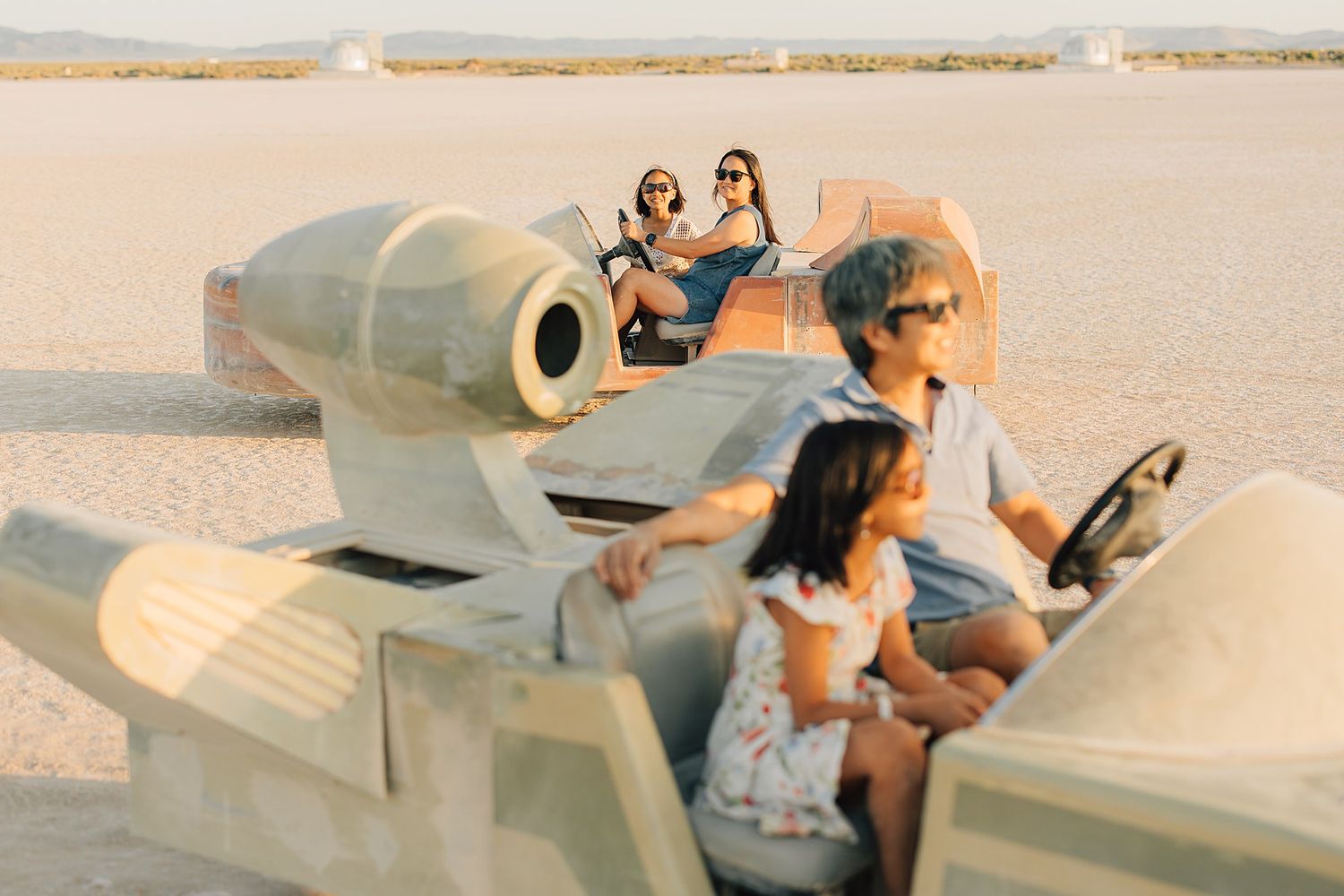People riding fun art car sculptures across a vast desert landscape at Burning Man festival.