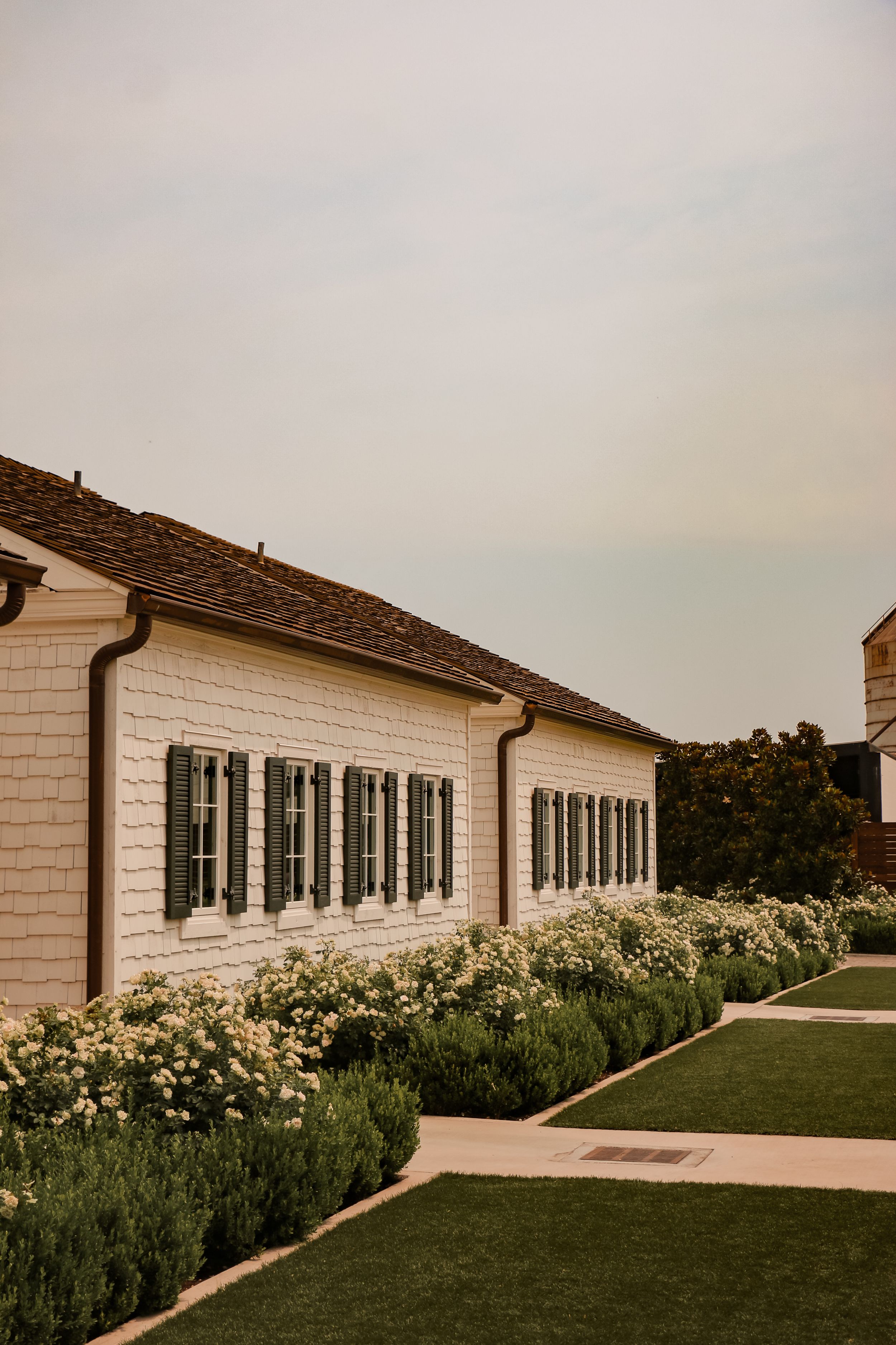 White colonial style building with black shutters and landscaped garden path.