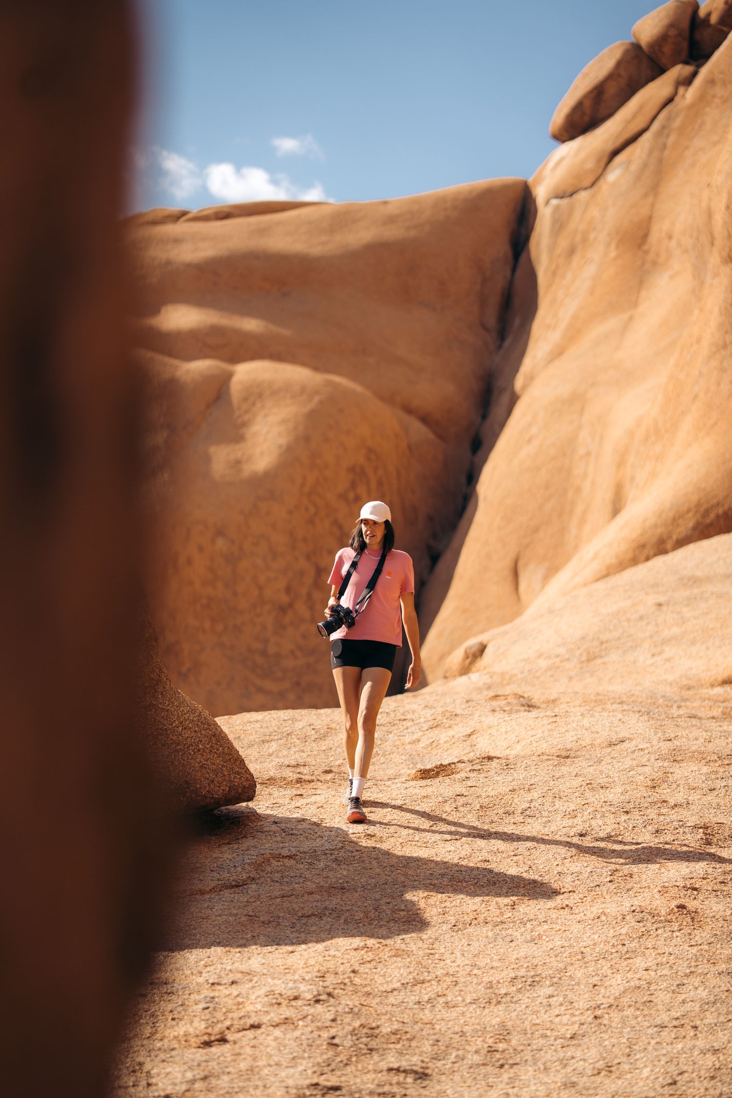 photographe qui marche dans un décor de roche granitique orange à spitzkoppe