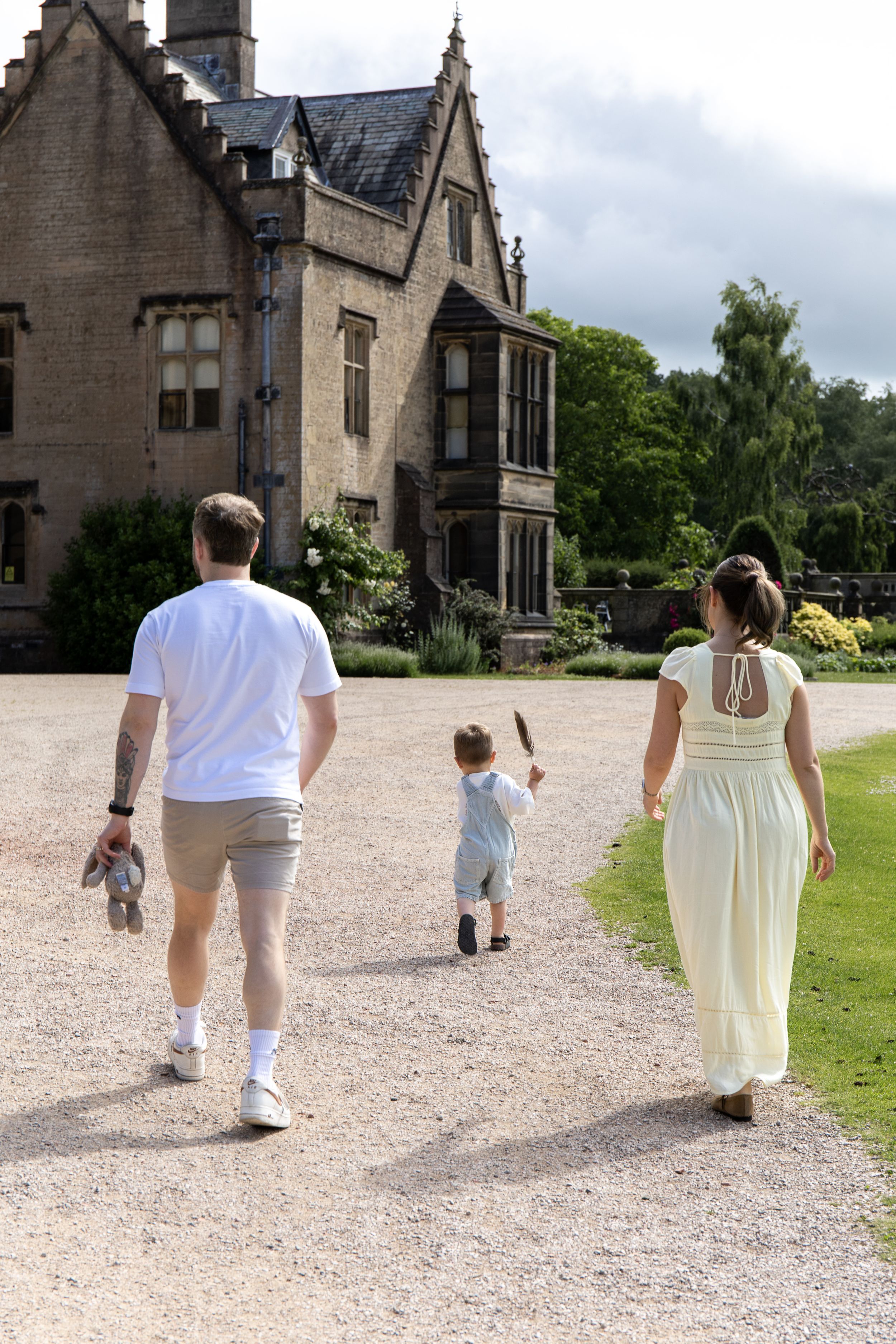 Family walking towards a grand historic manor house on a gravel path on a sunny day natural Outdoor family photoshoot Nottingham