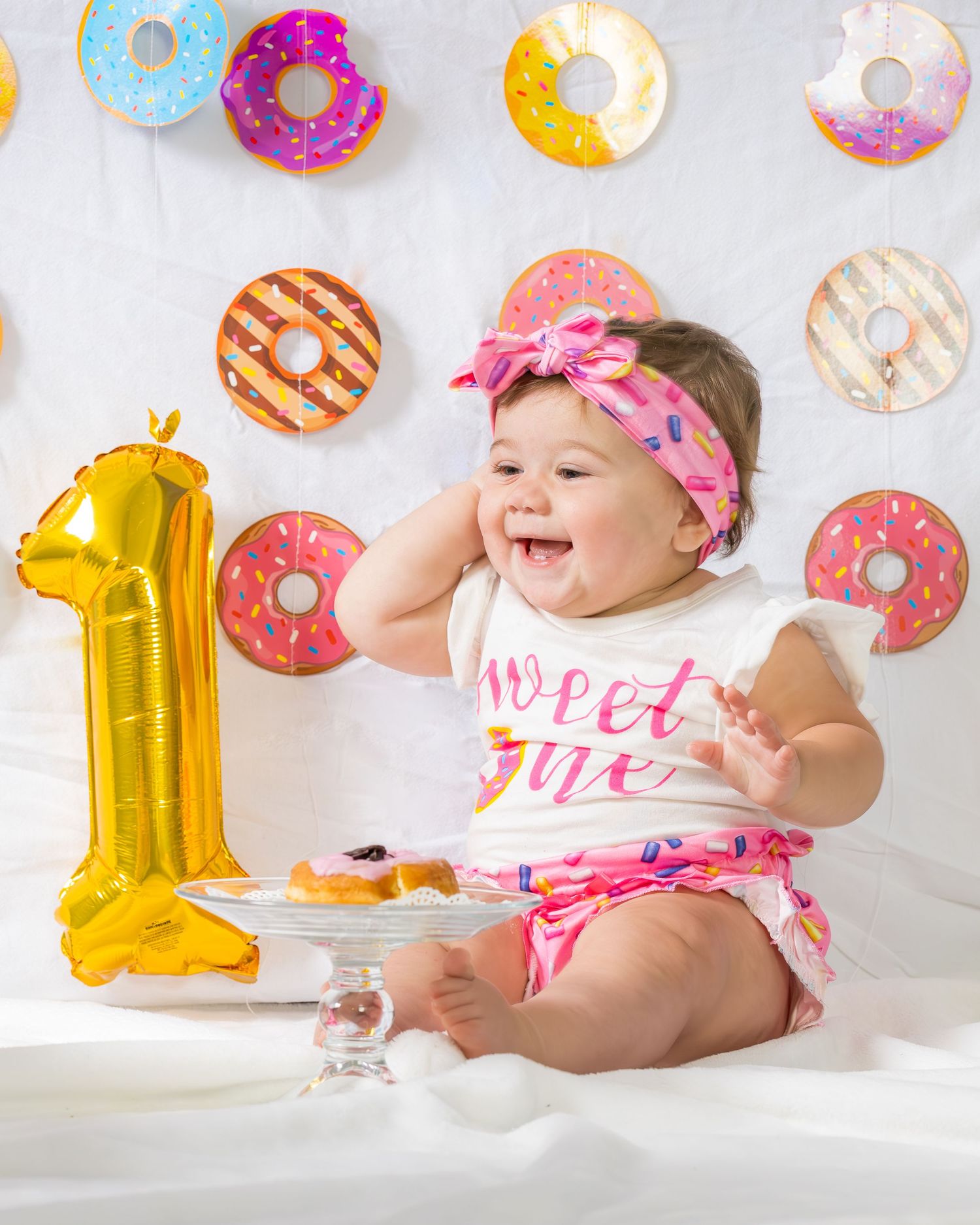 First birthday celebration setup with donut decorations and a gold number one balloon.