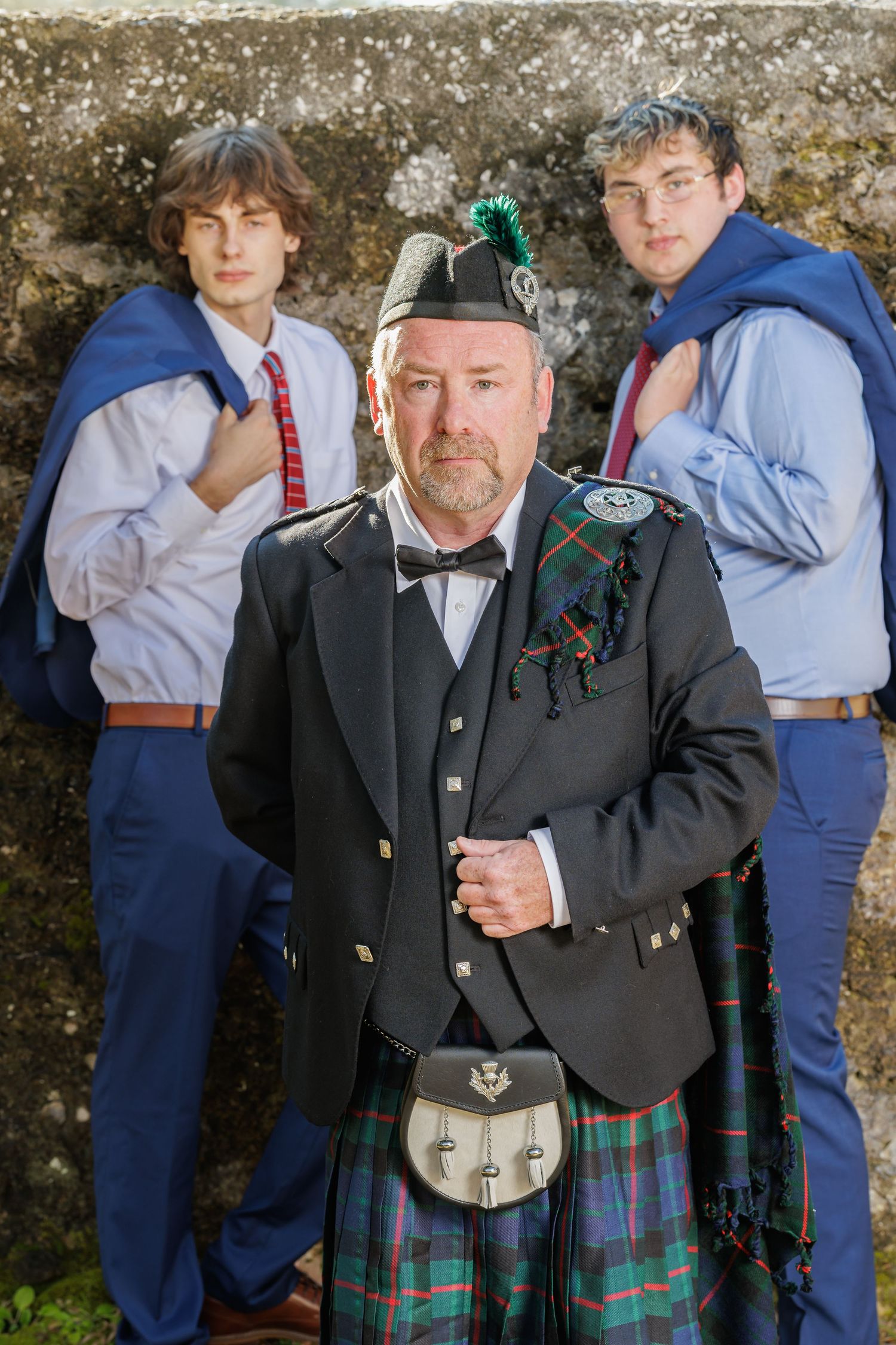 Group photo showing people in formal attire and Scottish kilts gathered outdoors.