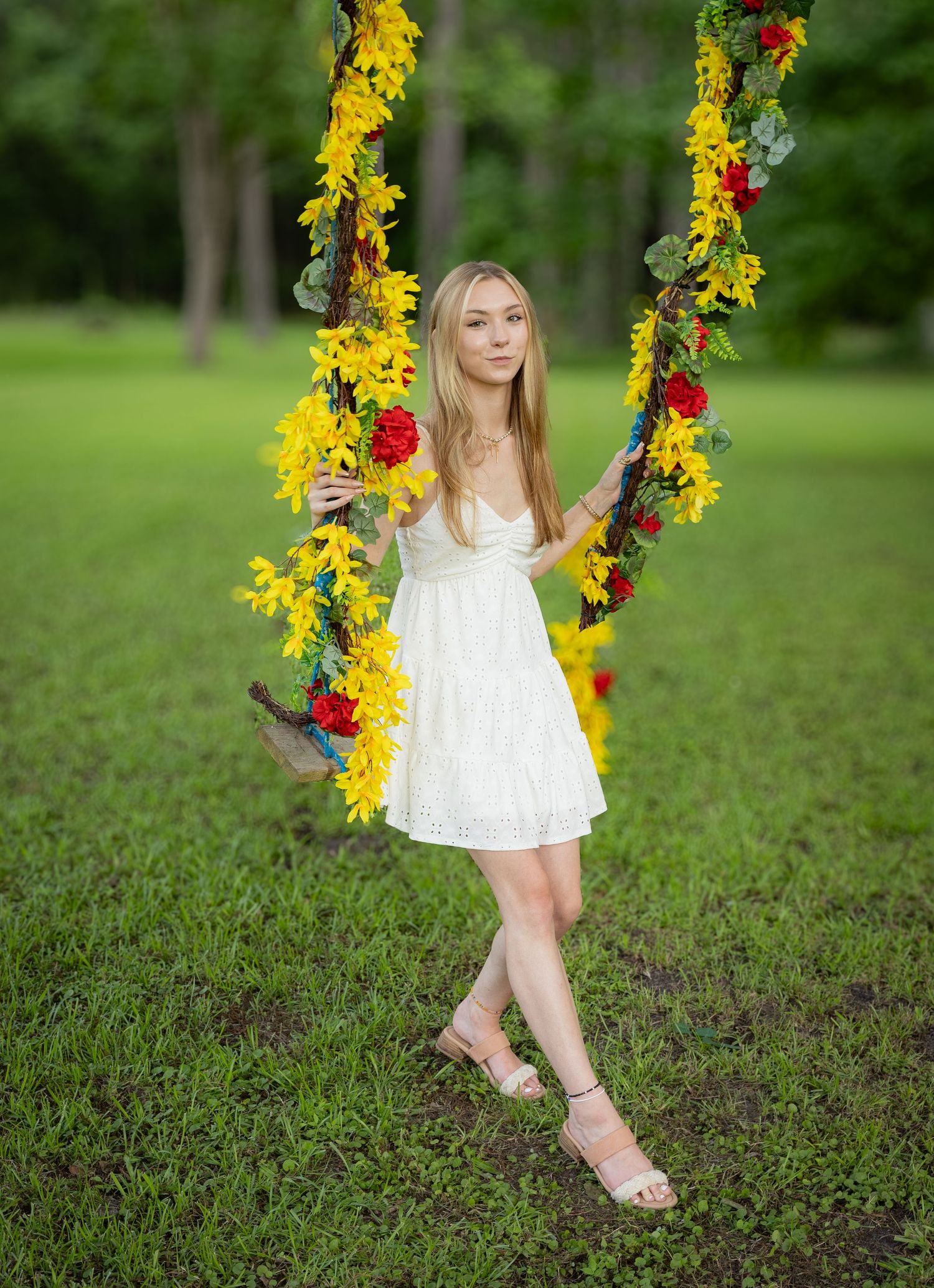 White dress portrait session on decorative floral swing in green garden.