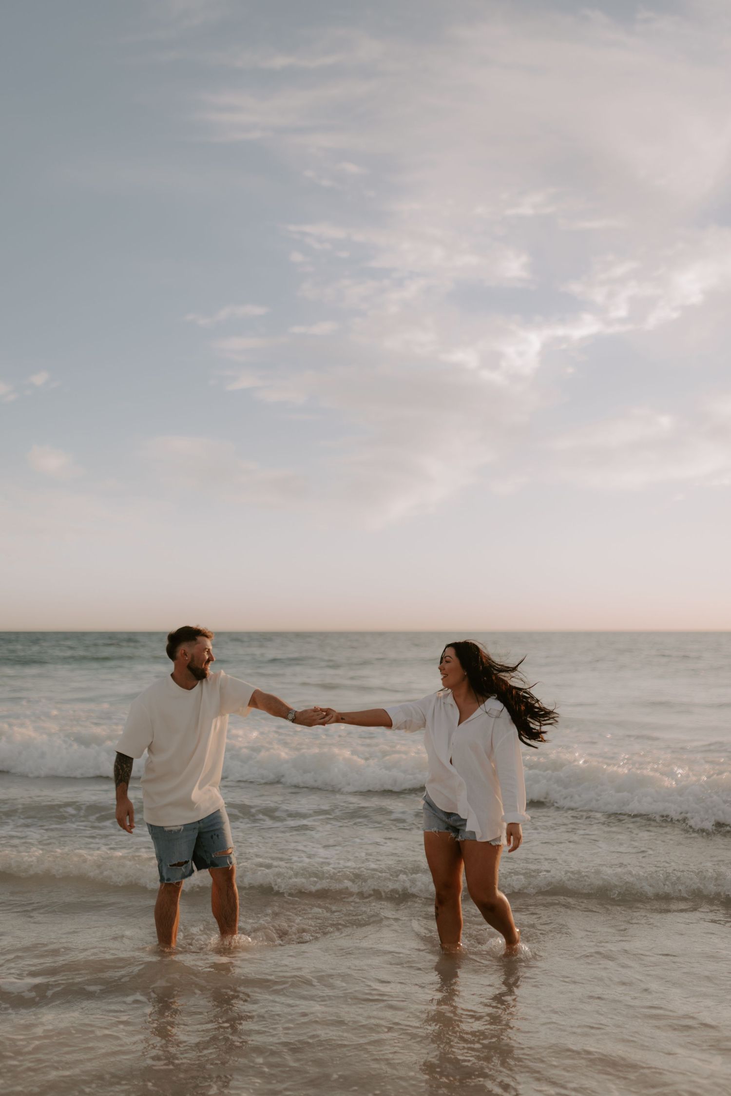 Couple sharing intimate moments in the ocean water during sunset photoshoot.