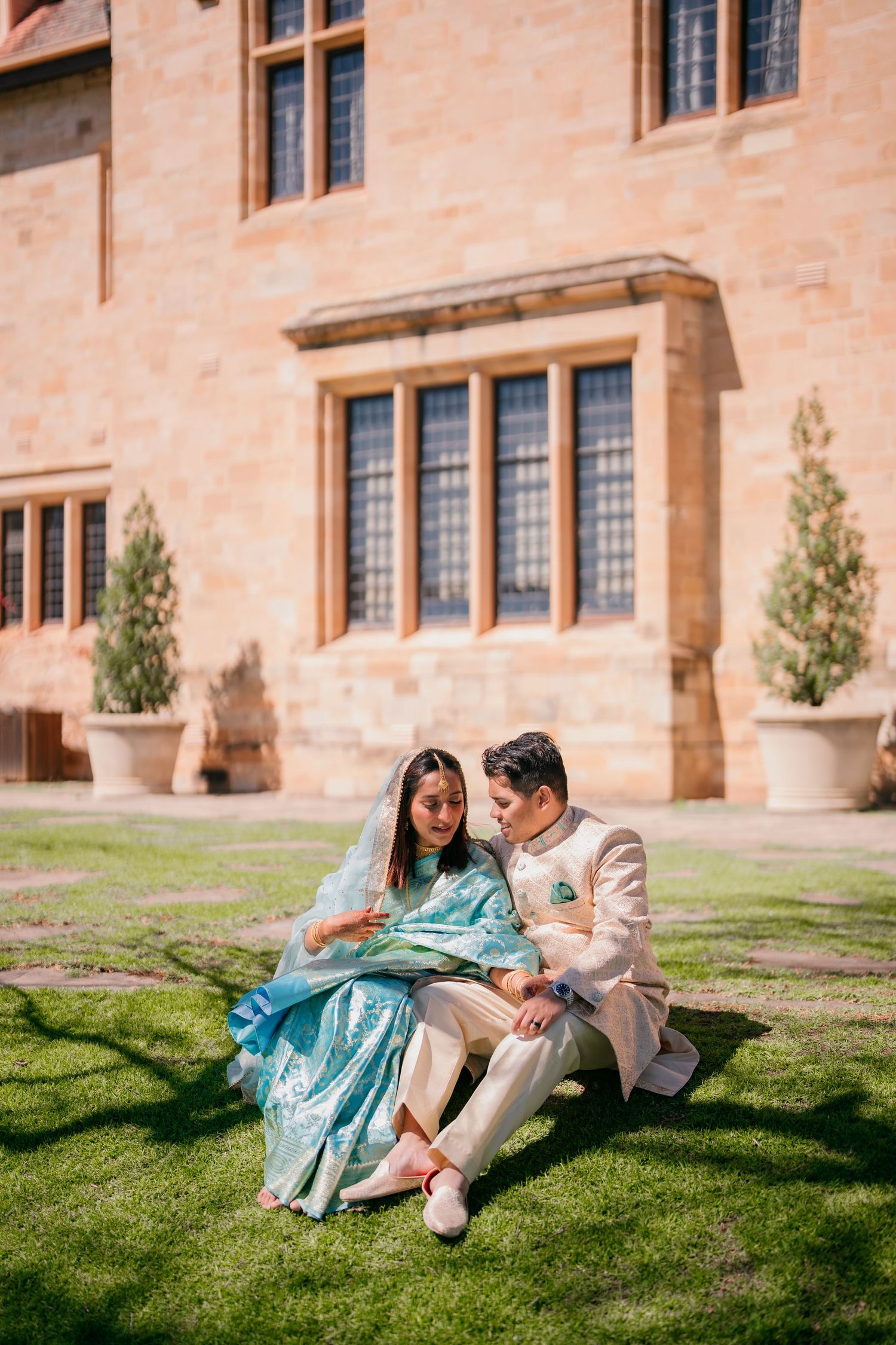 Couple sitting on the lawn below Carrick Hill manor windows, Adelaide pre-wedding shoot