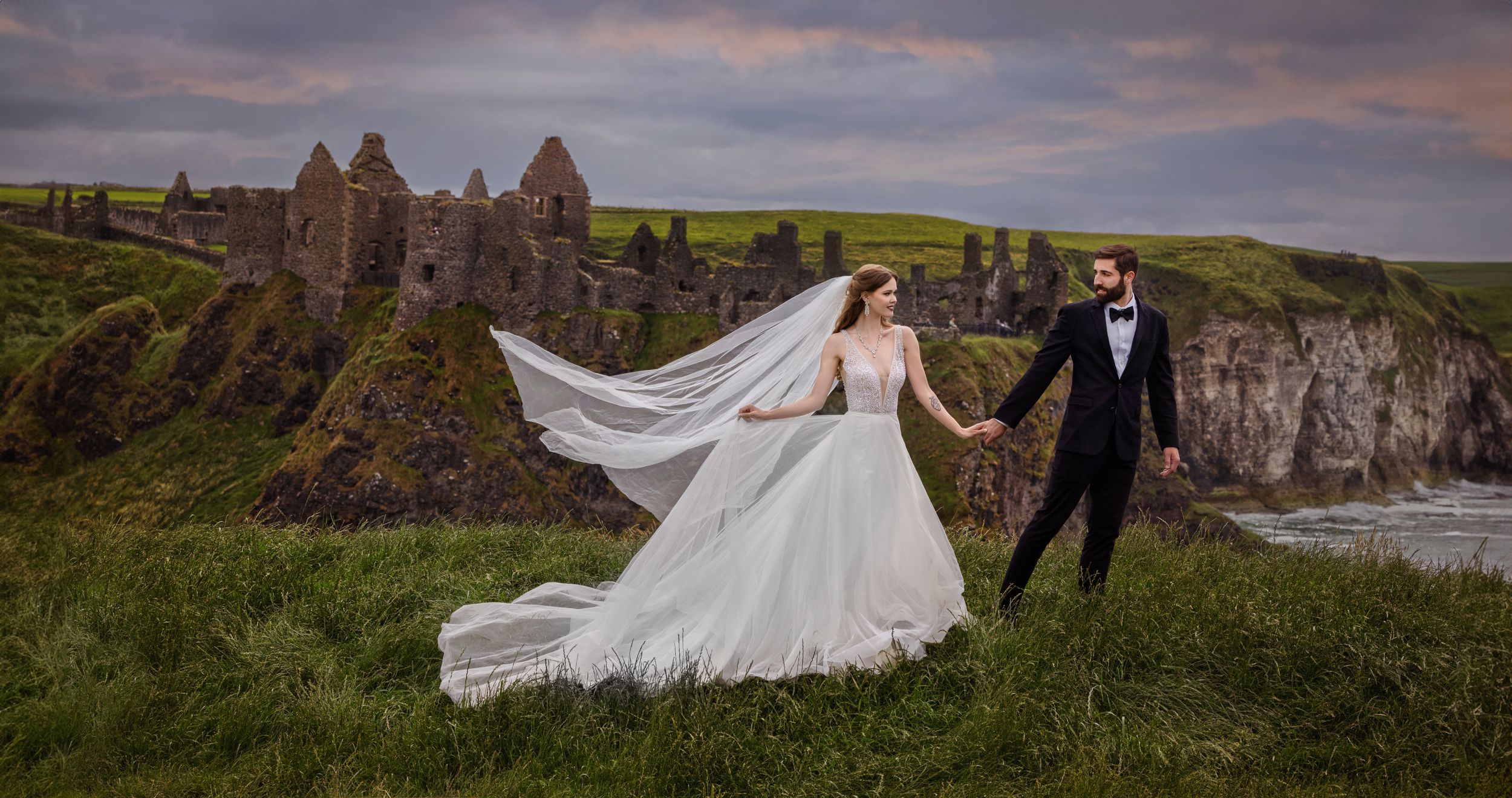 Bride and Groom standing in front of Dunluce Castle in Ireland