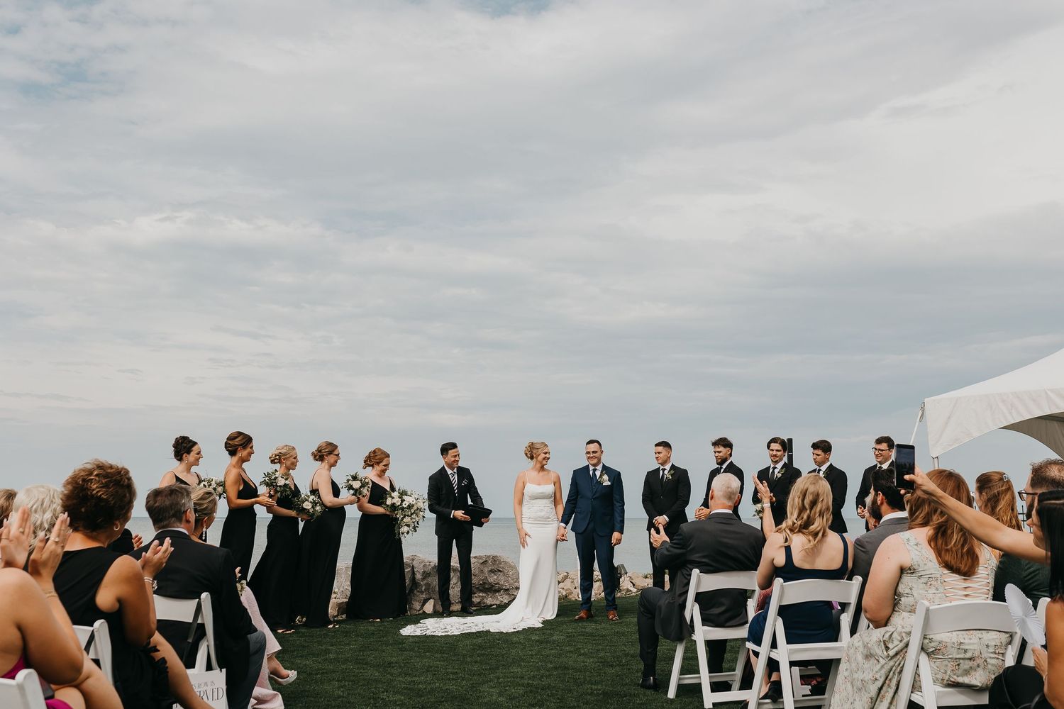 wedding party throwing confetti at newly married couple at urban field house in the summer