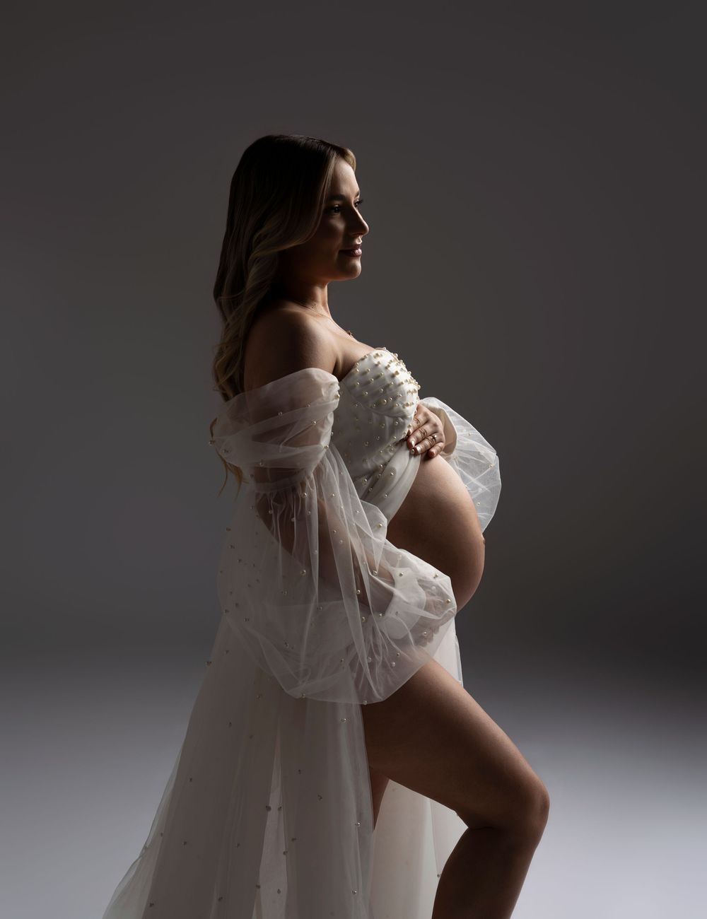 A dramatic artistic portrait of someone in a flowing white gown against a dark gray background in multiple poses.