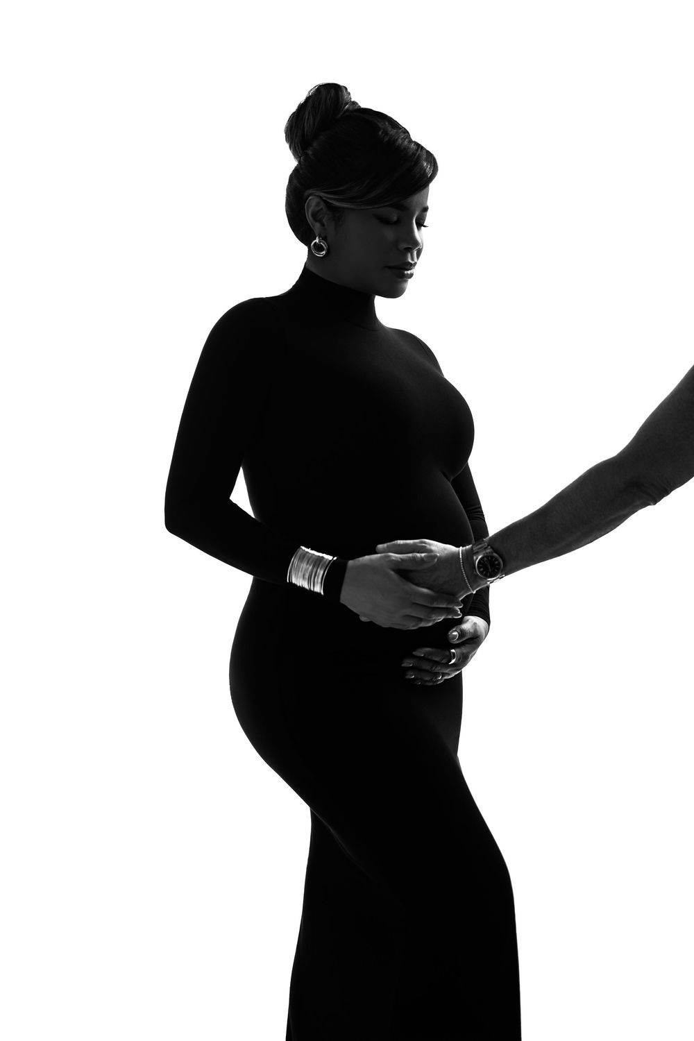 Elegant black and white silhouette of a pregnant woman in a form-fitting dress with a hand gently touching her baby bump.
