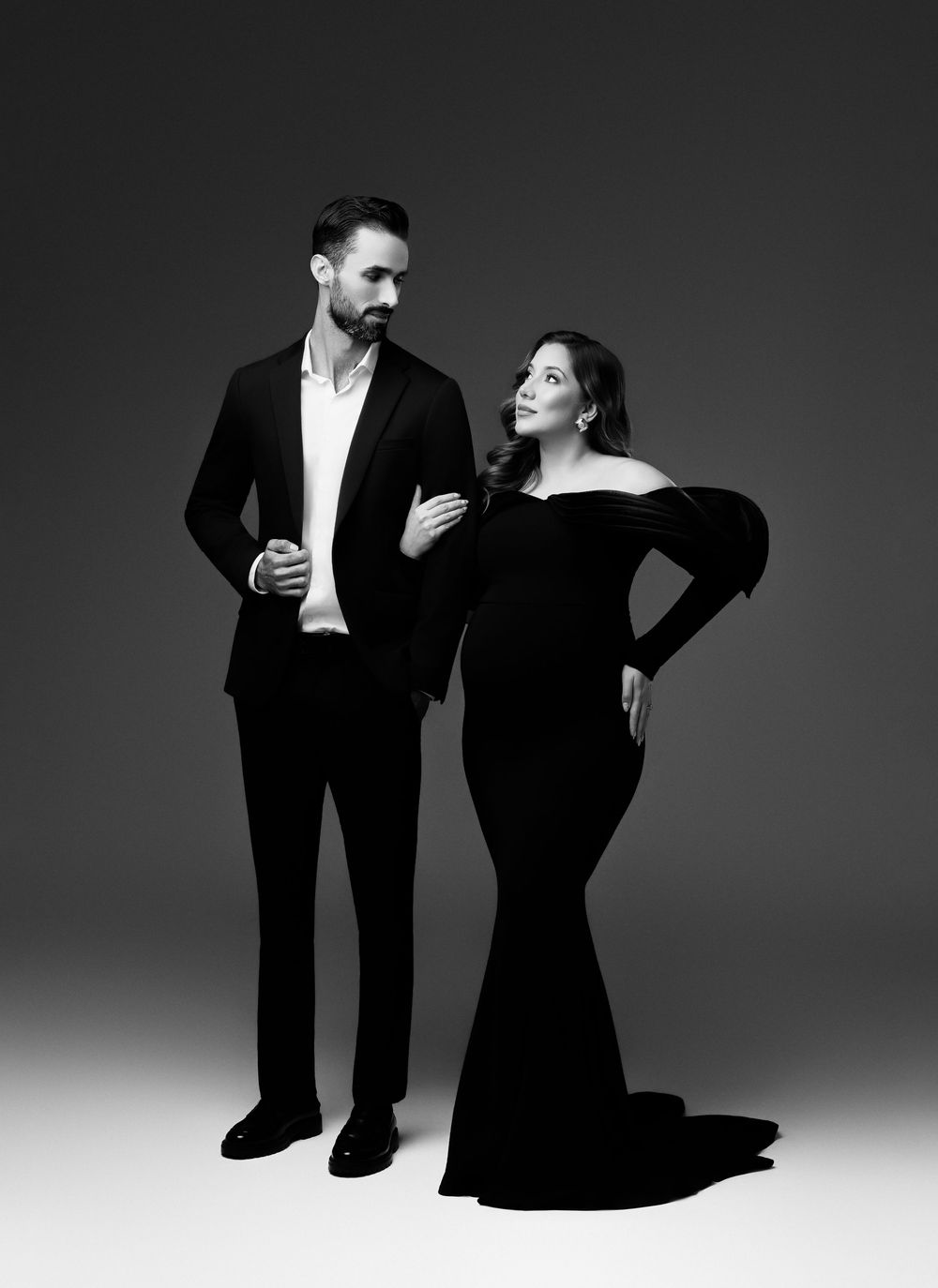 A black and white fashion photo series showing a couple in formal attire posing together in dramatic lighting.