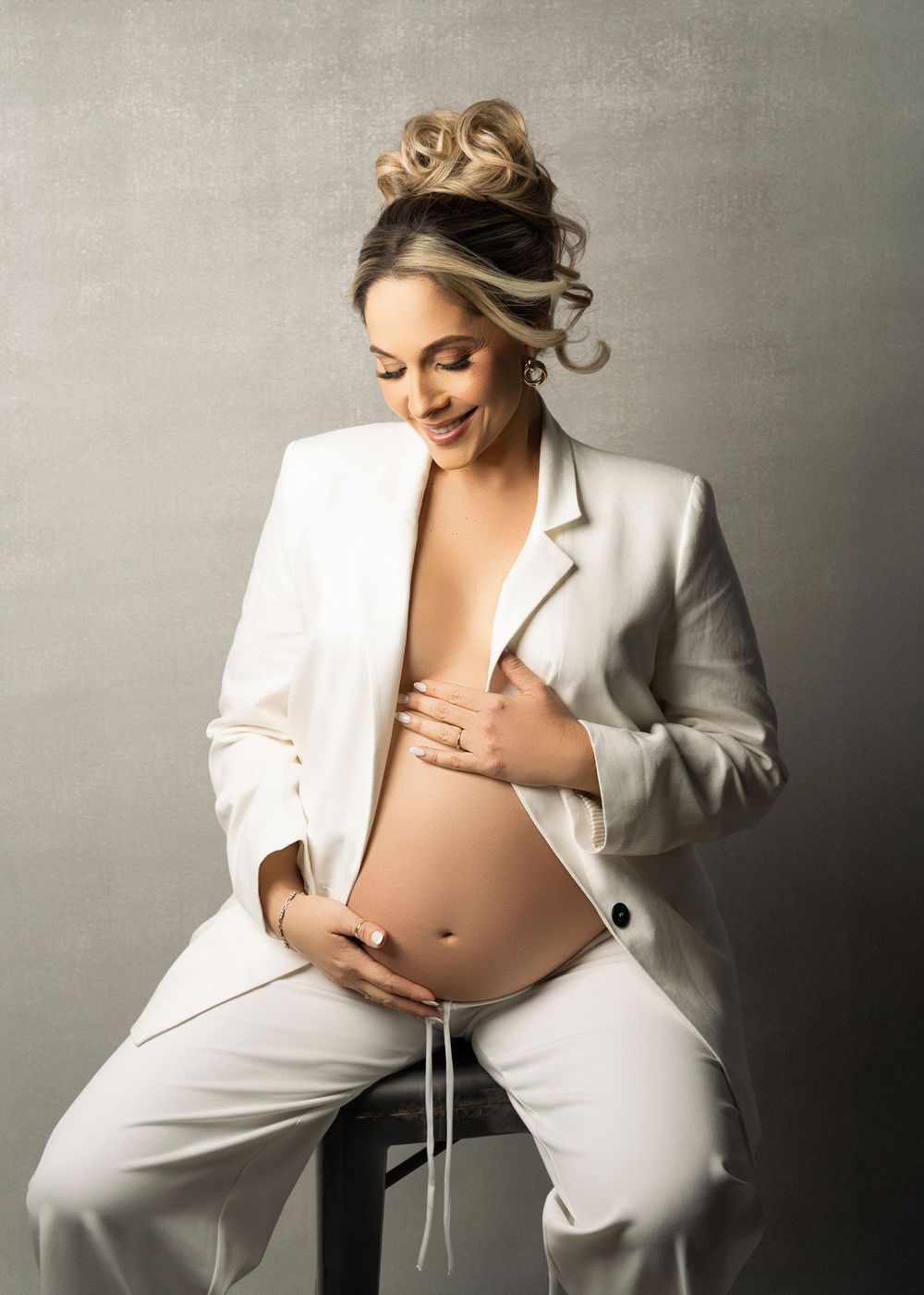 A creative maternity photo sequence showing a figure in a white blazer posing artistically against a gray backdrop.