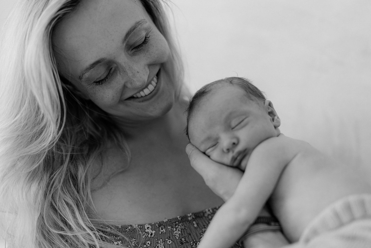 Black and white portrait of a tender moment between mother and sleeping baby.