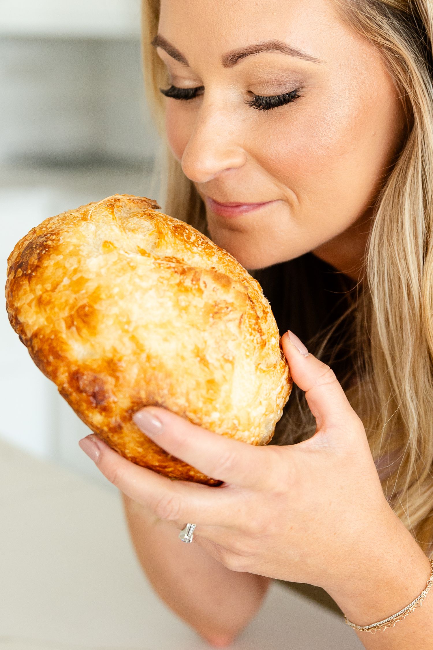 woman holding and smelling warm freshly baked sour dough bread