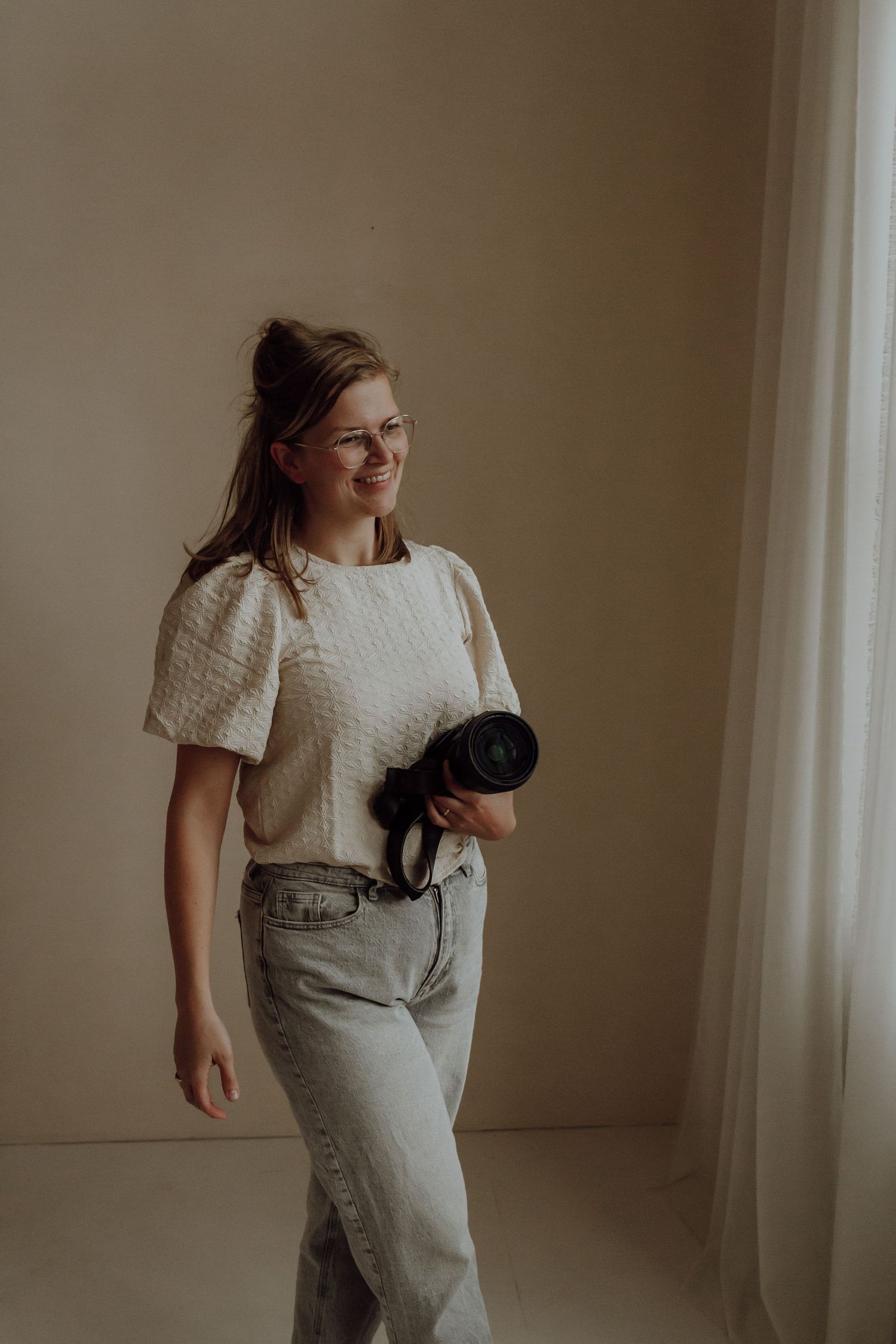 Zwart wit foto, vrouw kijkt lachend naar rechts. Zon schijnt.