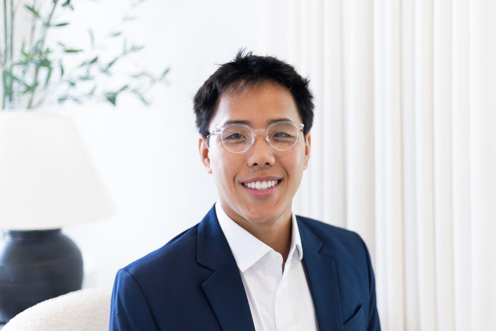 Professional headshot of a person in business attire with glasses against a white background.