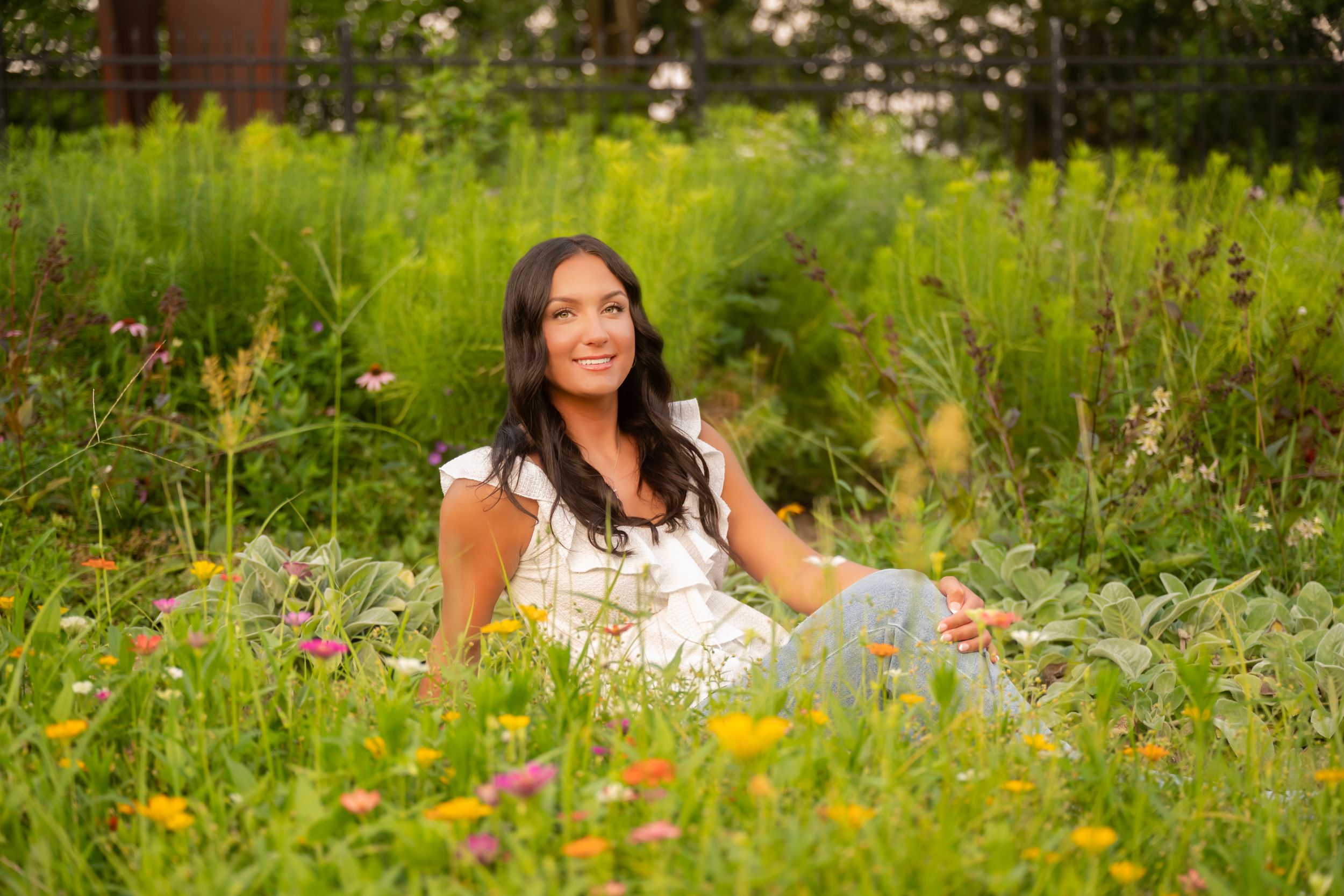 A person sits in a vibrant wildflower meadow filled with colorful blooms on a sunny summer day.