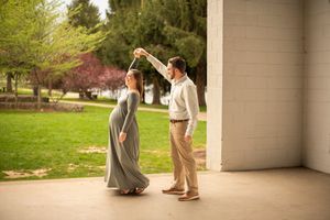 A couple shares a romantic dance moment under a covered porch with spring blossoms and greenery in the background.