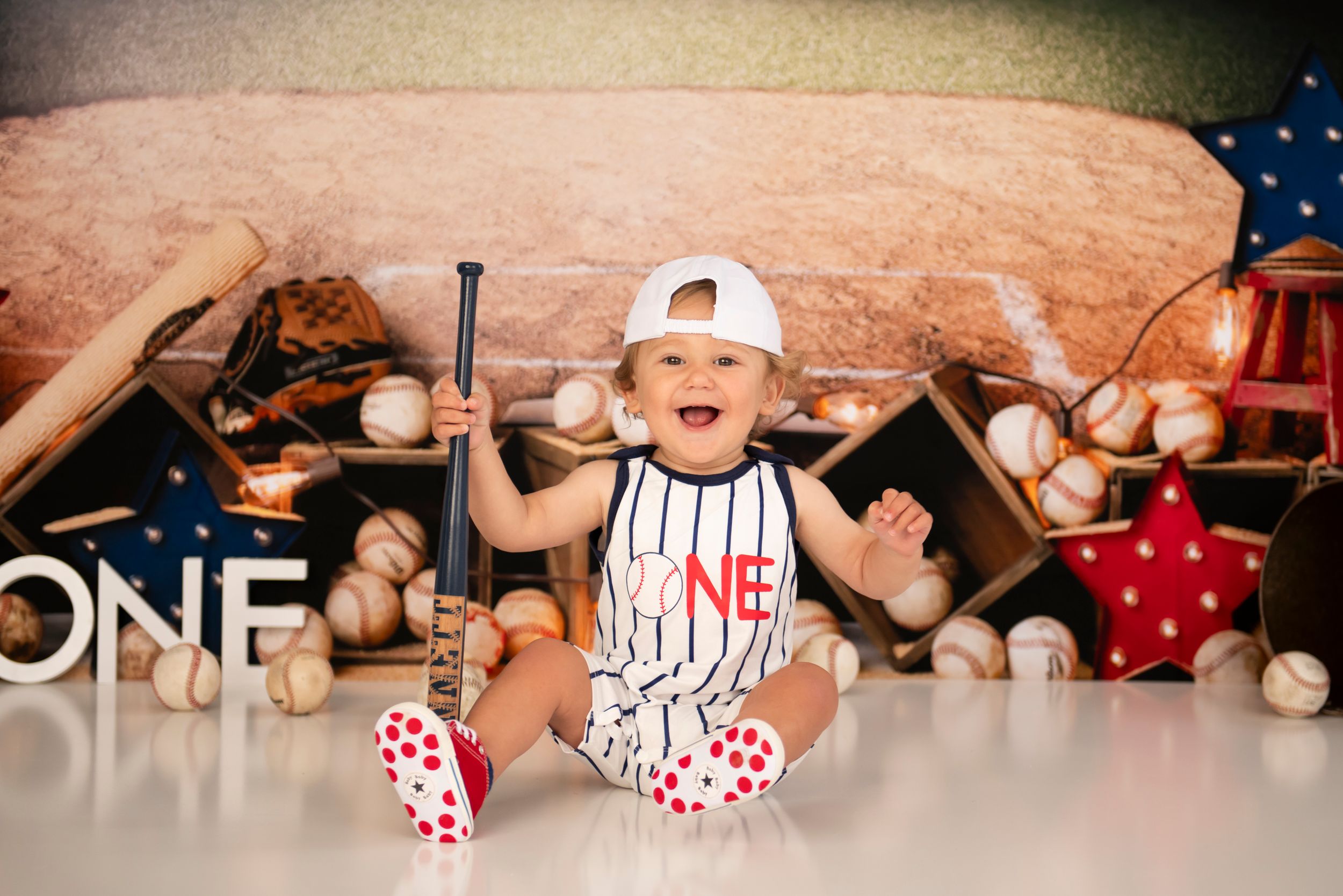 Baseball themed first birthday setup with excited baby in pinstripe outfit.