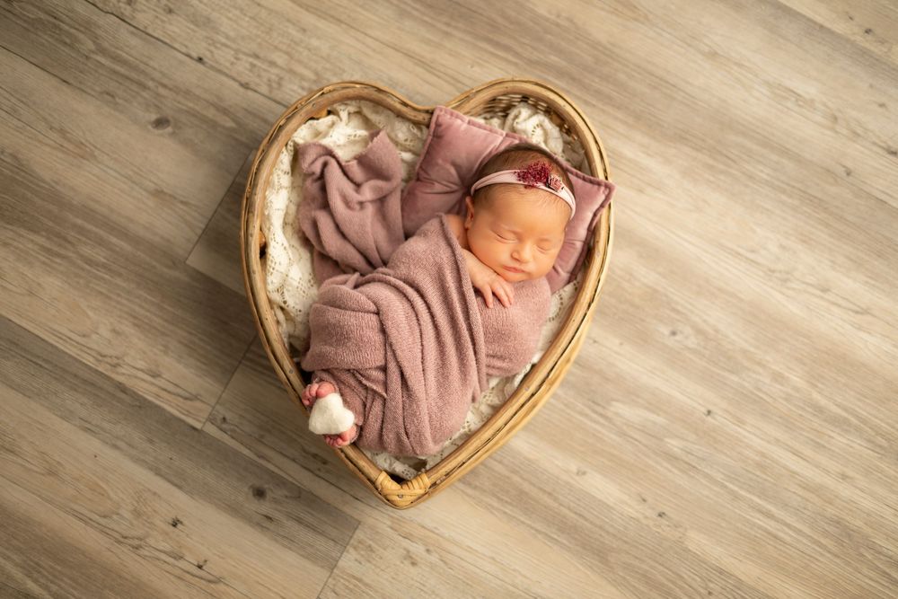 A sequence of heart-shaped wooden bowls with peach-colored fabric and flowers arranged on a light wooden surface.