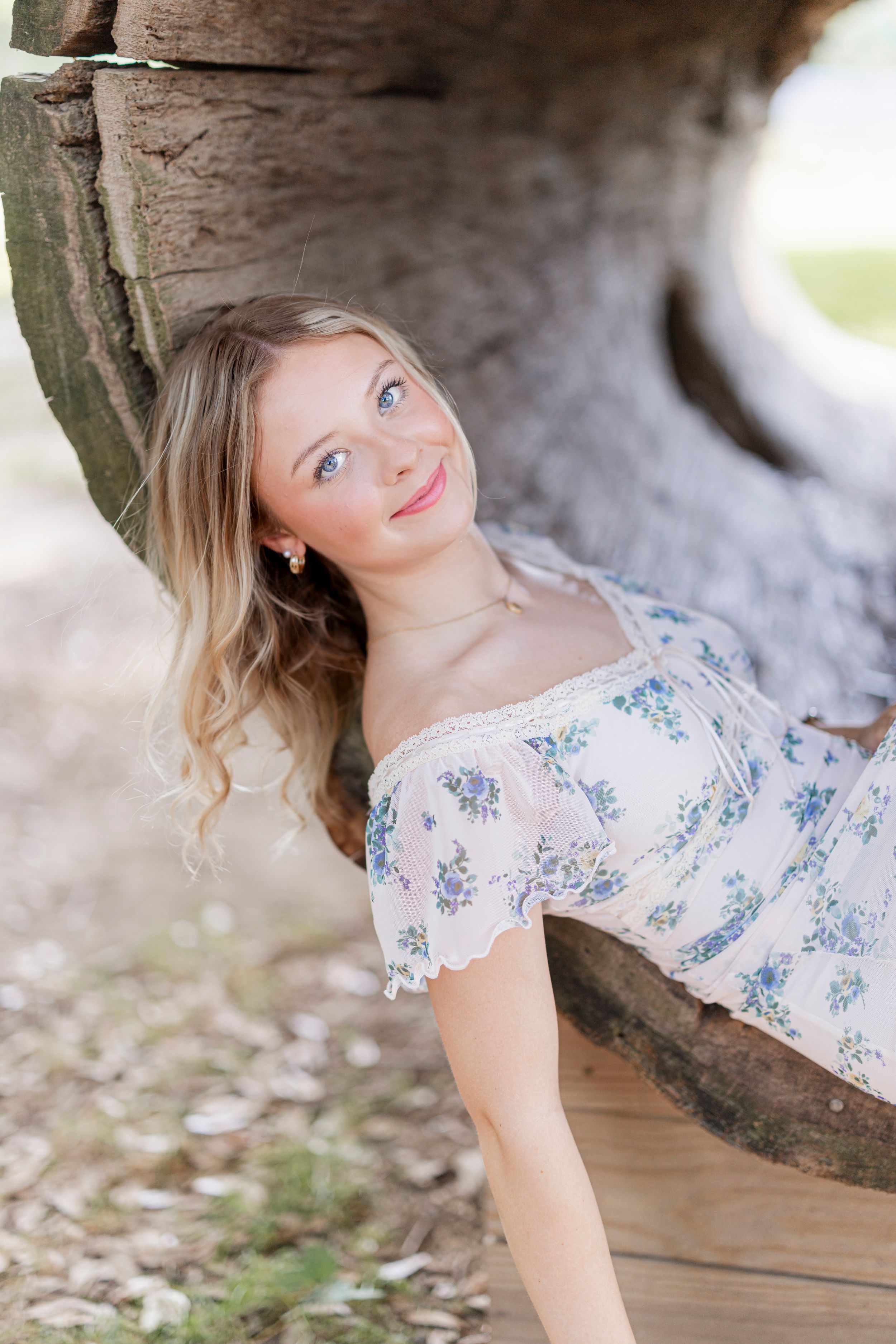 A set of artistic portraits showing a person in a floral dress posing beneath a tree canopy.