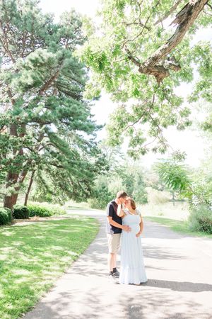 A romantic summer scene in a tree-lined park pathway with elegant white dress attire.