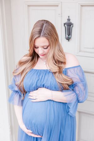 A woman in a flowing light blue off-shoulder maternity dress poses in a series of pregnancy photos.