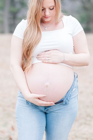 A series of maternity photos showing a woman in a white top and jeans cradling her baby bump in an outdoor setting.