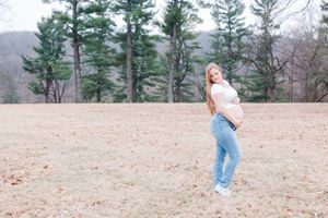 Someone does playful cartwheels across a sandy beach area with evergreen trees visible in the background.