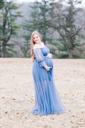 Mother and daughter in matching light blue tulle dresses embrace during outdoor fall photo shoot.