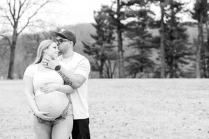 Winter engagement photos show a couple embracing in a snowy field with evergreen trees in the background.